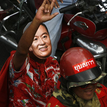 A demonstrator wears a mask of former prime minister Thaksin Shinawatra as anti-government protesters move through central Bangkok in March 20. (Chaiwat Subprasom, Reuters)