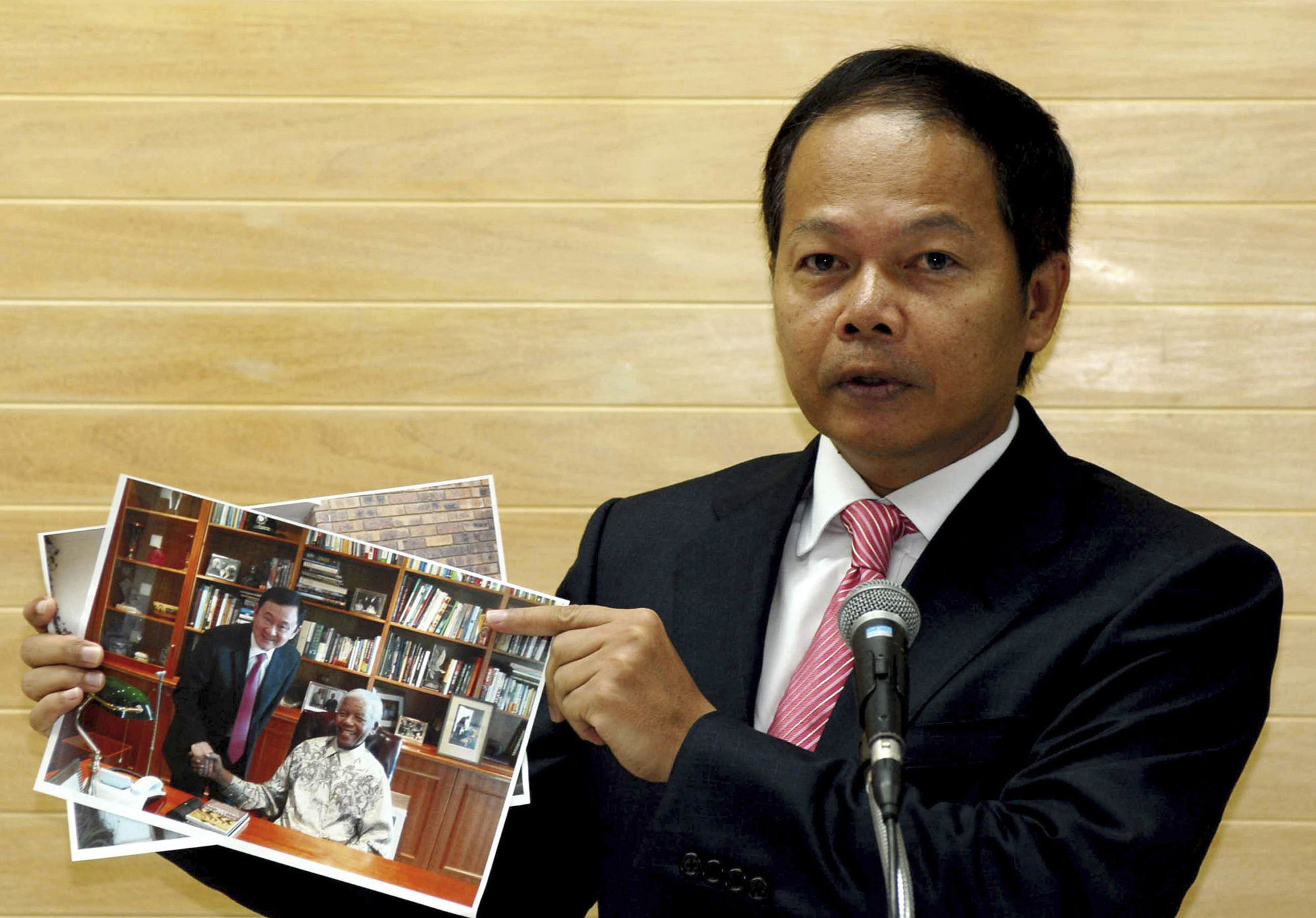 Noppadol Pattama, a legal adviser for ousted Thai prime minister and fugitive from justice Thaksin Shinawatra, shows photos of Shinawatra meeting former South African president Nelson Mandela in Johannesburg last month. (Phue Thai Party, AP)