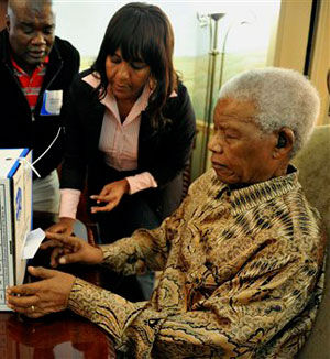 Former South African president Nelson Mandela casts an early ballot in the local government elections at his home in Johannesburg on May 16, assisted by his granddaughter, Ndileka Mandela. (AP/GCIS)