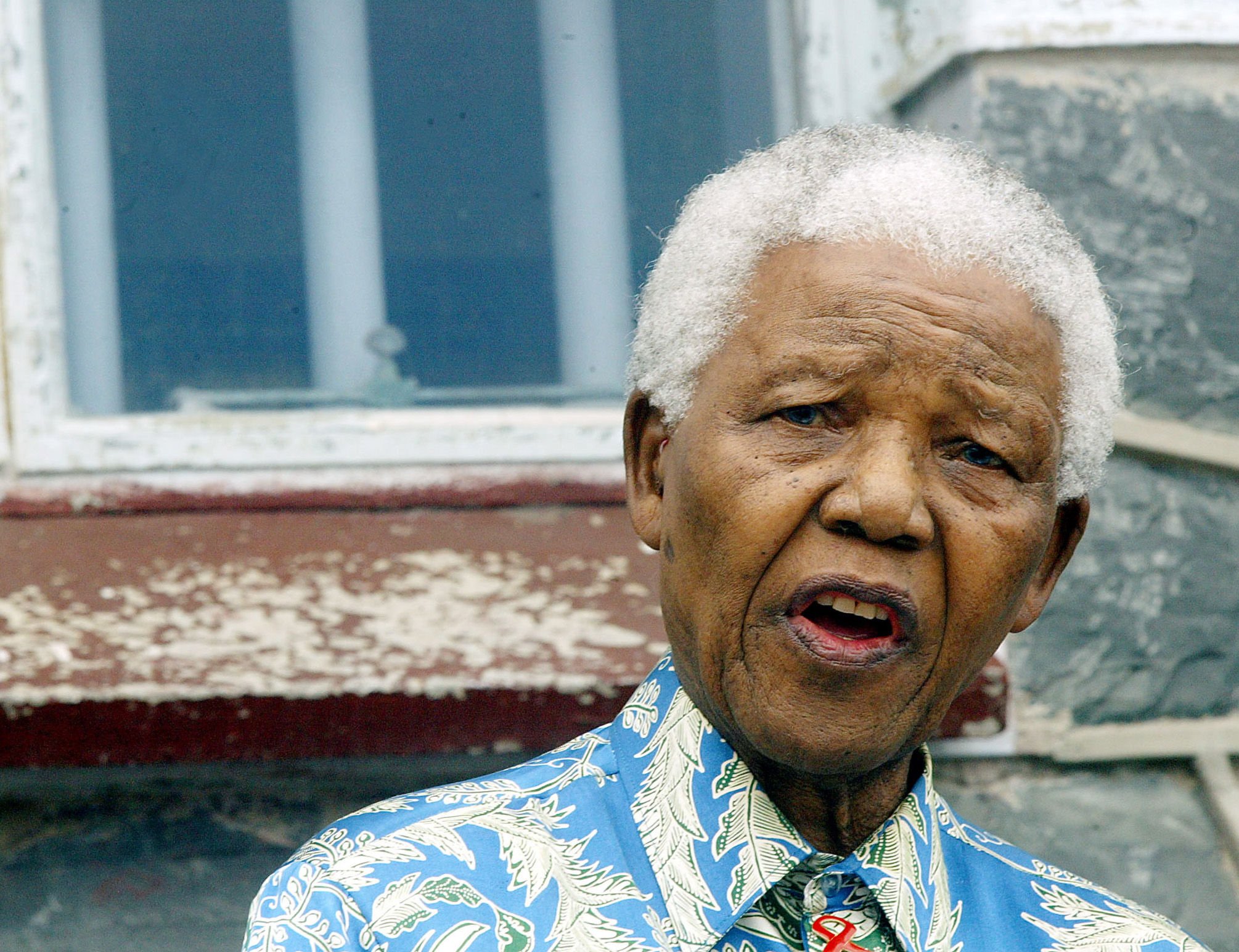 Nelson Mandela addresses musicians beneath the window of his prison cell on Robben Island, November 2003. Mandela visited the island with stars who were to perform at the 46664 Aids benefit concert.